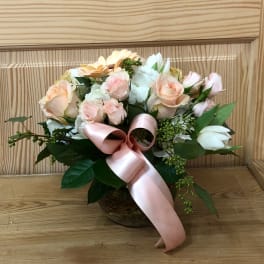 Bouquet of pale pink and white flowers with a pink ribbon in a basket