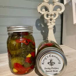 Two jars of pickles on a countertop, one upright and one lying on its side