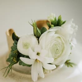 White ranunculus and small white blossoms arranged in a compact bouquet