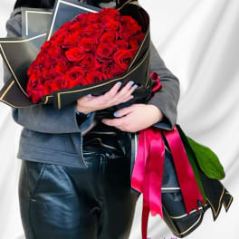 Large bouquet of red roses wrapped in black paper with pink ribbon