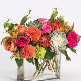 Mixed bouquet of pink and orange flowers in a clear glass vase