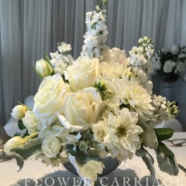 White floral centerpiece in a silver pedestal bowl