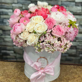 Pink and white roses in a white hat box with a pink ribbon