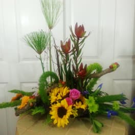 Colorful floral arrangement with sunflowers, pink roses, and tall tropical blooms