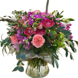 Pink and purple mixed flower arrangement in a clear glass vase with a silver ribbon bow.