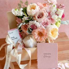 Pastel bouquet in a gift box with chocolates, a candle, and a card