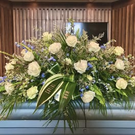 Large white rose and blue flower casket spray on a silver casket
