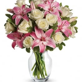 Pink lilies and white roses arranged in a clear glass vase