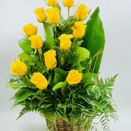 Yellow roses arranged in a woven basket with lush greenery