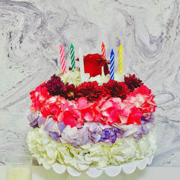 Round flower cake with colorful blooms and striped candles