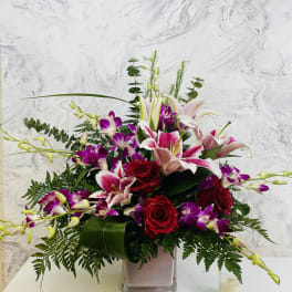 Bouquet of red roses and pink lilies in a square glass vase