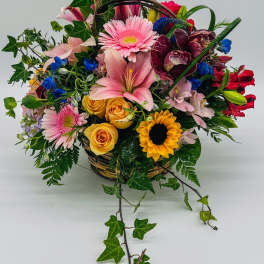 Mixed flower basket with pink lilies, roses, and sunflowers