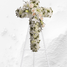 White floral cross on a stand with lilies and roses