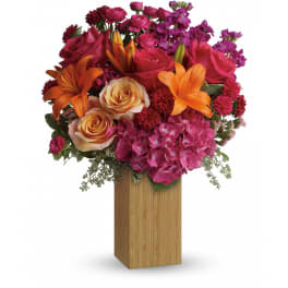 Vibrant arrangement of orange lilies, pink roses and hydrangea in a tall rectangular wood vase