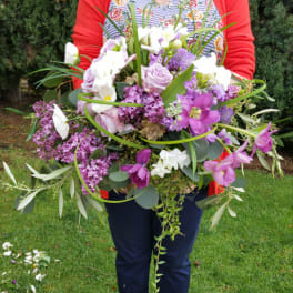 Large bouquet of purple and white flowers held outdoors
