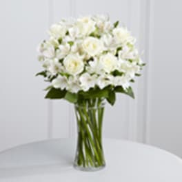 White roses and white alstroemeria in a clear glass vase