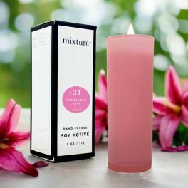 Pink soy votive candle beside its box with stargazer lilies in the background