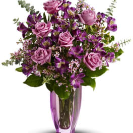 Purple roses and mixed blooms in a purple glass vase