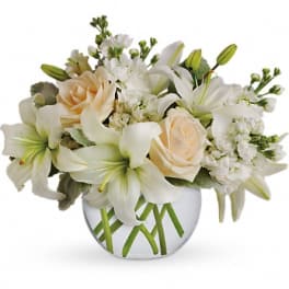White lilies and pale roses arranged in a round glass vase