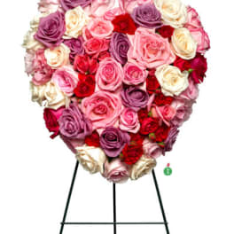 Heart-shaped standing arrangement of pink, red, and lavender roses on a metal easel