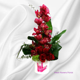 Red orchids and roses arranged in a white vase with a pink love graphic