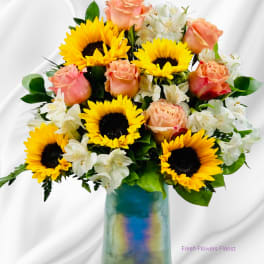 Sunflowers, peach roses, and white alstroemeria in a blue glass vase