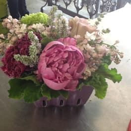 Pink peony arrangement in a purple container with mixed blooms