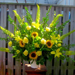 Yellow floral arrangement with sunflowers, roses, and lilies in a white vase