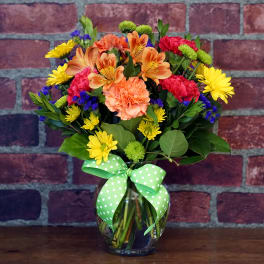 Colorful mixed bouquet in a glass vase with a green polka-dot bow