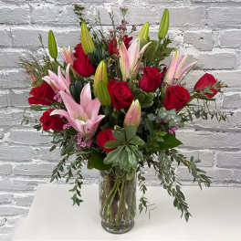 Red roses and pink lilies arranged in a clear glass vase