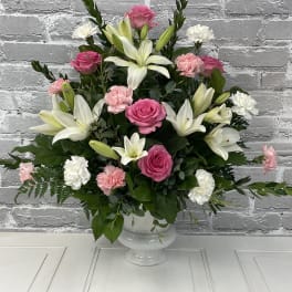 Pink roses and white lilies arranged in a white vase