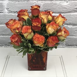 Orange and yellow roses in a red glass vase