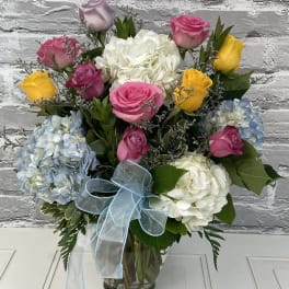 Bouquet of roses and hydrangeas in a glass vase with a blue ribbon