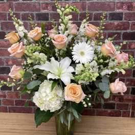 Peach roses and white lilies in a glass vase