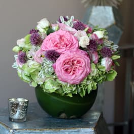 Pink and white roses arranged in a dark green vase