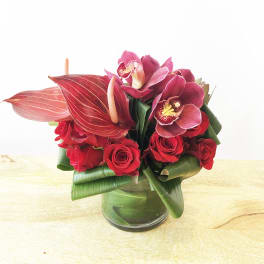 Red roses and pink orchids arranged in a glass vase