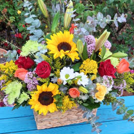 Basket arrangement with sunflowers, roses, lilies, and daisies