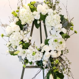 White floral wreath on an easel with roses and lilies
