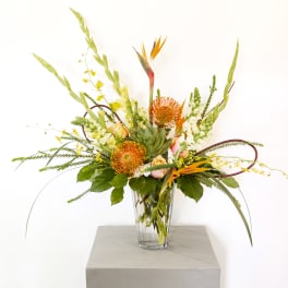 Tropical floral arrangement in a clear glass vase with orange blooms
