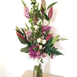 Tall bouquet of lilies, chrysanthemums, and white roses in a glass vase