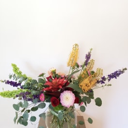 Mixed bouquet in a clear glass vase with red, pink, purple, and yellow blooms