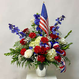 Red, white, and blue floral arrangement with an American flag in a vase