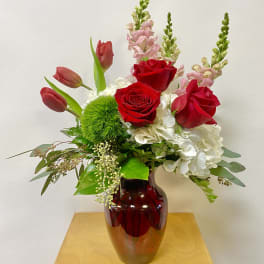Red roses and pink tulips in a red glass vase