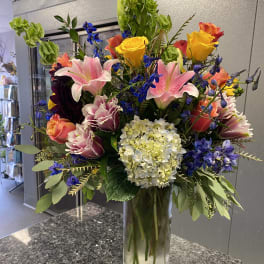Mixed bouquet of roses, lilies, and hydrangea in a glass vase