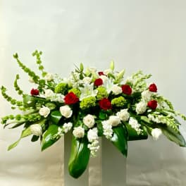 Large floral arrangement of red and white roses with lilies on a pedestal