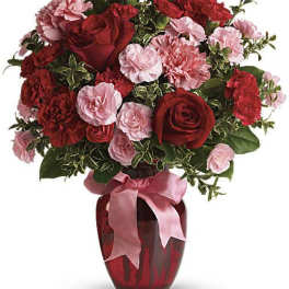 Red roses and pink carnations in a red vase with a pink ribbon