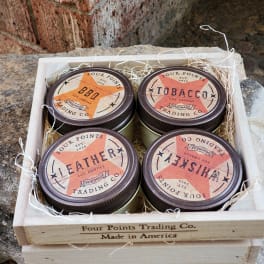 Four scented candles in a wooden crate with shredded filler