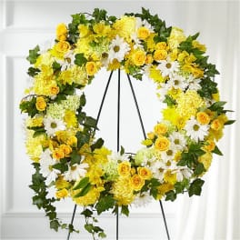Yellow and white floral wreath with roses, daisies, and mums on a standing easel