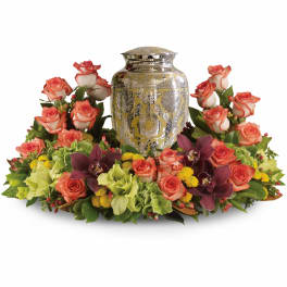 Cremation urn surrounded by peach roses, green hydrangeas, yellow mums, and burgundy orchids