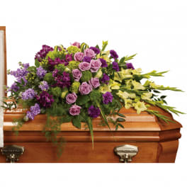 Purple and lavender casket spray with yellow flowers on a wooden coffin